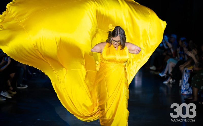 adaptive-fashion-runway-2025-denver Missing limb model walks down runway with bright yellow dress billowing around her at denver's fashion week 2025. Photo by Weston Mosburg