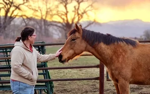 inclusive-community-spaces-denver woman petting a horse with the colorado rocky mountains in the background